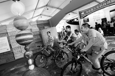 自転車による発電を體験する子供たち