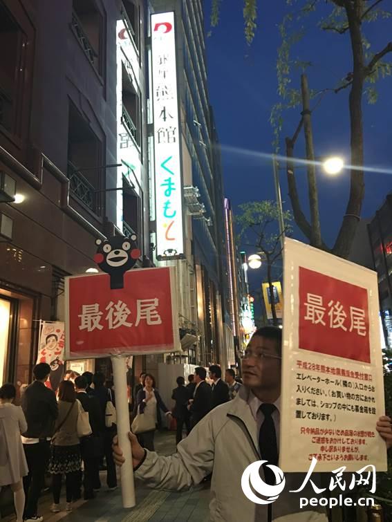 「最後尾」のプラカードを持って誘導(dǎo)する「銀座熊本館」スタッフ