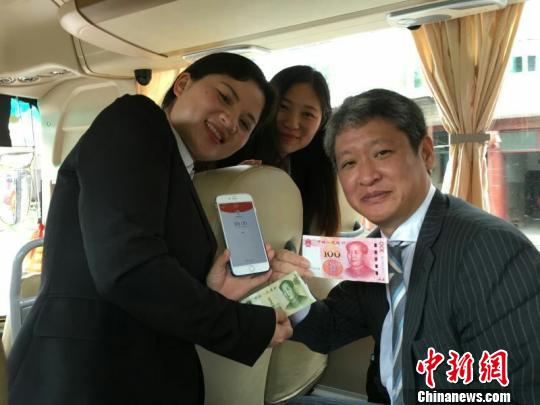 寫真：ガイド（左）から現(xiàn)金100元をうけとり、1元のお釣りを出す石井宏明さん（右）