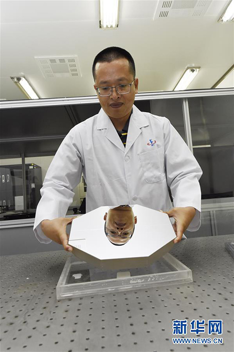 地上望遠(yuǎn)鏡の反射鏡を手にする科學(xué)研究者。