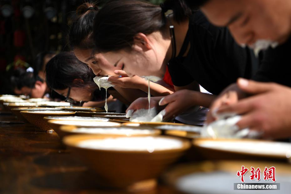 両手で豪快にすくって競うヤクヨーグルトの早飲み大會　四川省
