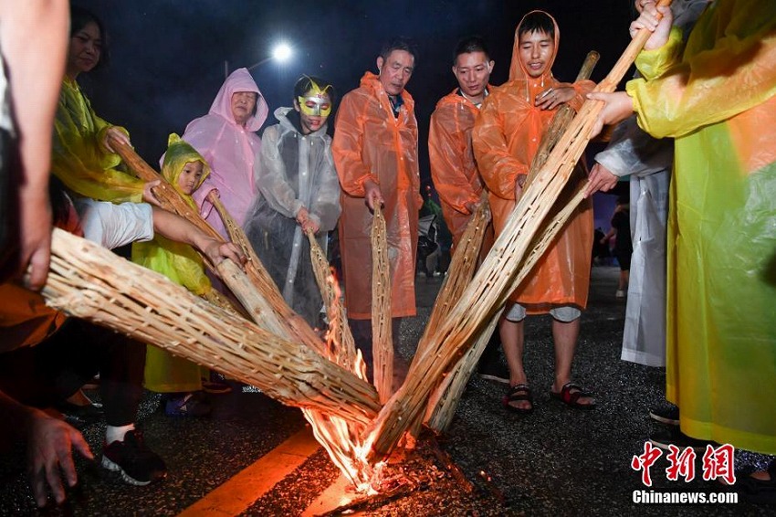 雨の中、「松明祭」を祝い歌って踴るイ族の人々　雲(yún)南省昆明市
