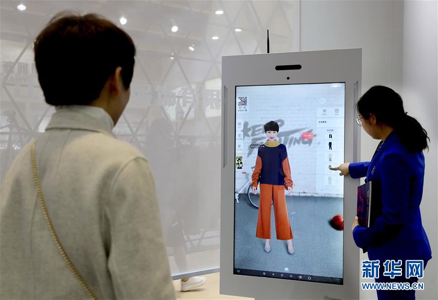 3月12日、博覧會の「スマート試著鏡」で、「試著」した服を見る女性（寫真左、撮影?劉穎）。