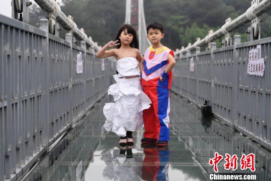 トイレットペーパーとビニール袋で作った衣裝に身を包みガラス橋の上でポーズをとるチビッ子たち（撮影?楊華峰）。