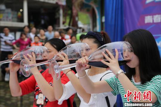 早飲み競(jìng)爭(zhēng)で大きなグラスに入ったワインを飲む參加者ら(撮影?楊孝永) 。