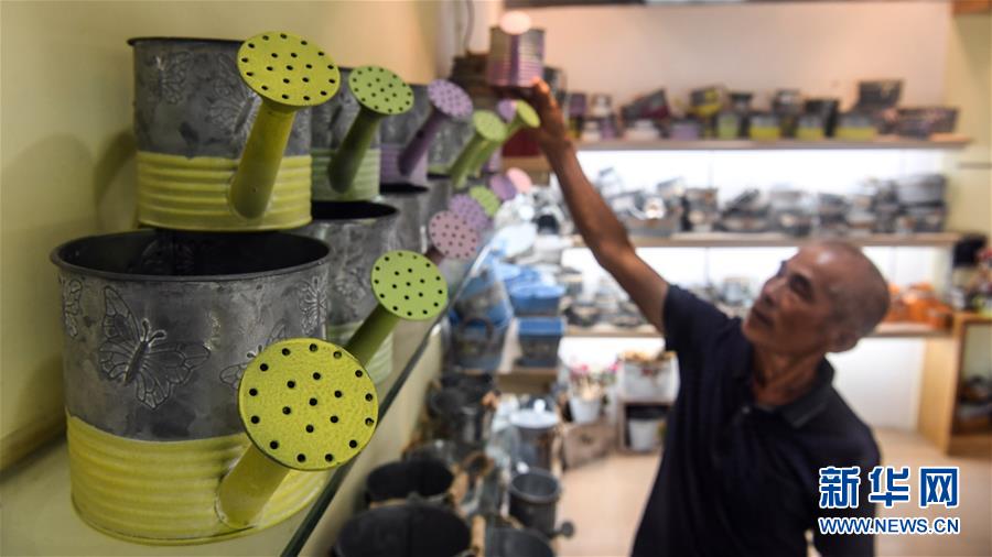 7月4日、欽州市高嶺工蕓品工場(chǎng)で、不用品を材料としたエコ手工業(yè)製品を一ヶ所にまとめて並べる男性（撮影?張愛林）。