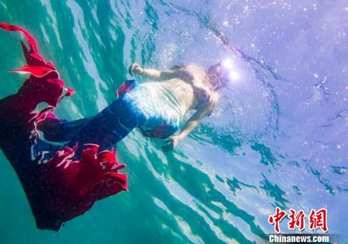 人魚姿の女性ダイバーが青く澄んだ海を優(yōu)雅に泳ぎ回る様子（撮影?駱雲(yún)飛）。