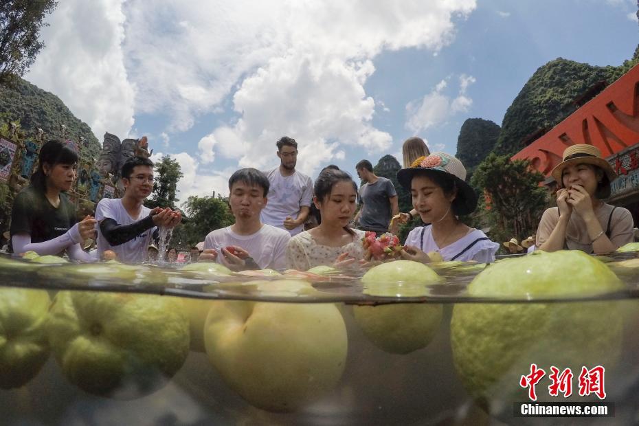 ひんやりした水に浸かりながらフルーツを楽しむ人々（撮影?陳飛）。