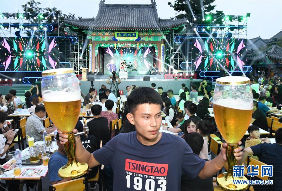 山東省青島市の國際ビール祭り(即墨古城會(huì)場(chǎng))で大きなビールグラスを両手に持つ男性（7月12日撮影?李紫恒）。