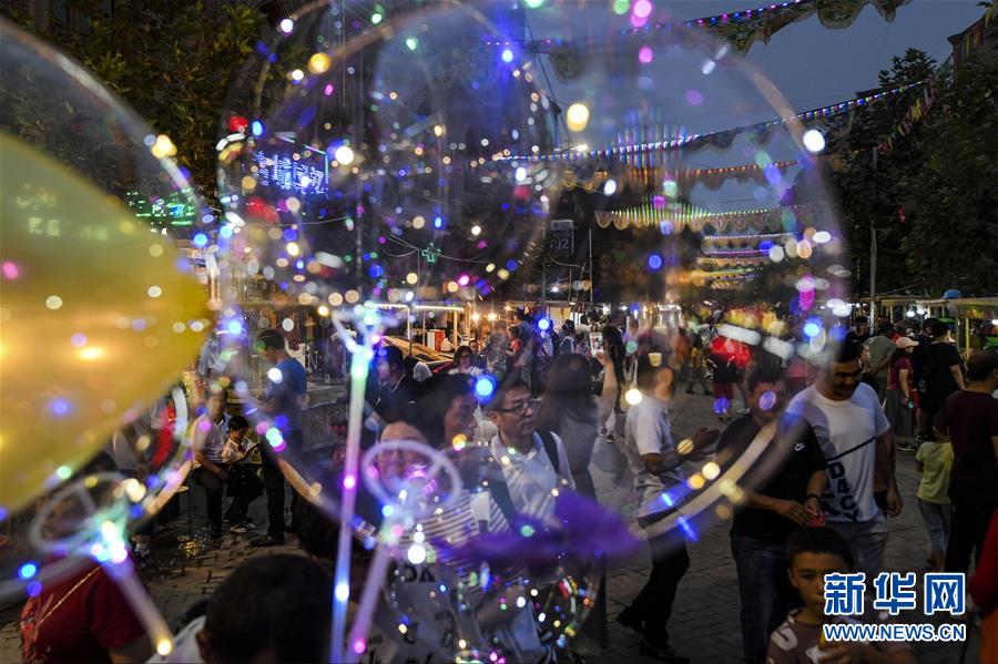 新疆ウイグル自治區(qū)喀什（カシュガル）市歐爾達(dá)路のナイトバザールで、観光やショッピングを楽しむ人々（8月18日、撮影?王菲）