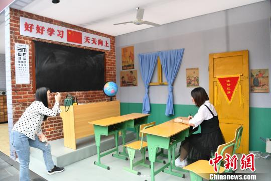 懐かしい教室の様子を再現(xiàn)したスペースで、記念撮影する人（撮影?張浪）。