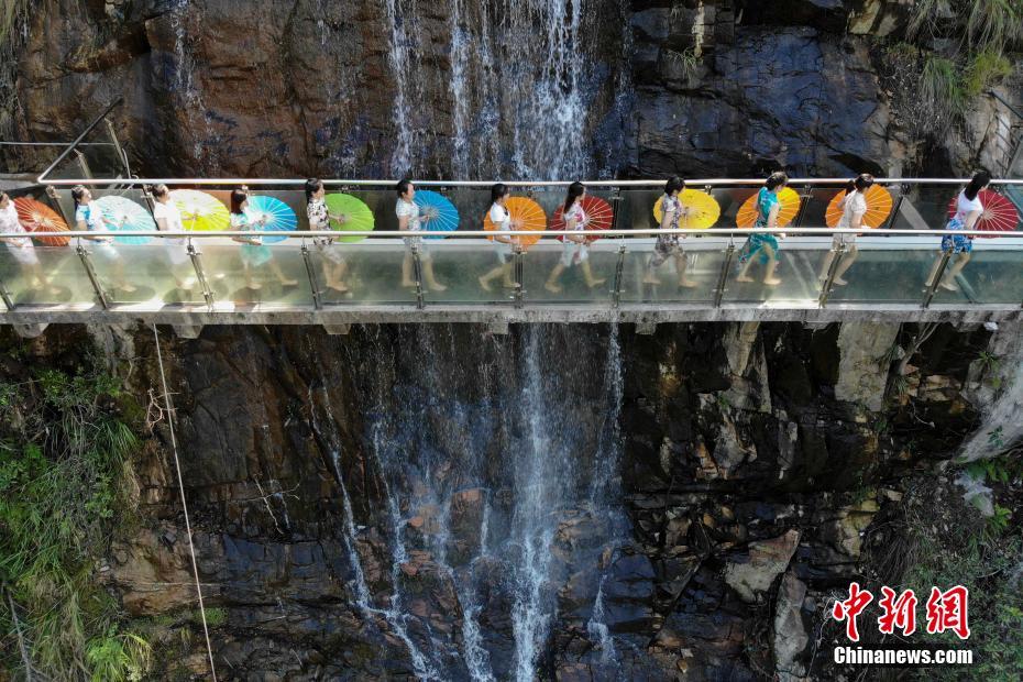 滝の前の桟道を歩くチャイナドレス姿の女性たち（9月26日、上空から撮影?楊華峰）。