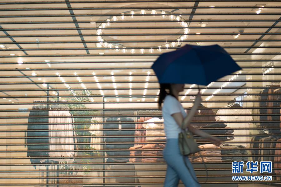 10月13日、香港地區(qū)銅鑼灣（コーズウェイベイ）で、早めに営業(yè)を終了した店の前を通り過ぎる市民（撮影?張金加）。