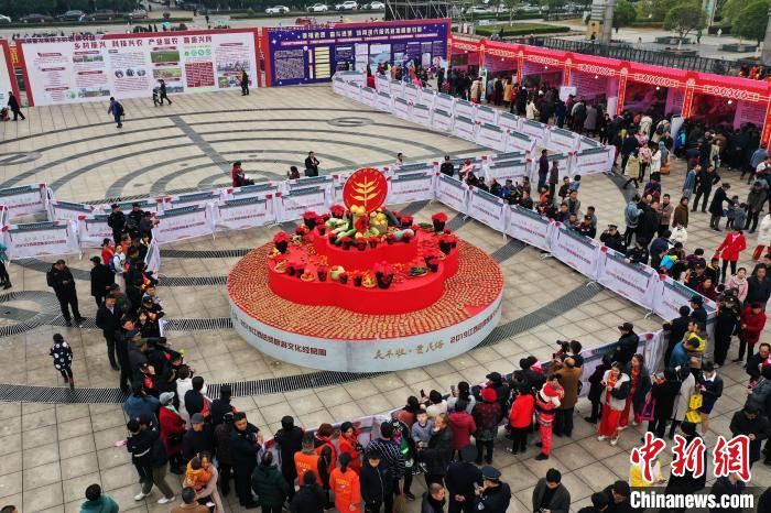 11月30日、江西省南昌市進(jìn)賢県の人民広場(chǎng)で、赤い布の敷かれた?jī)倚韦闻_(tái)の上に並べられた1萬匹近い蒸しガニと無料で配られるカニを受け取ろうと並ぶ人々（撮影?劉占昆）。