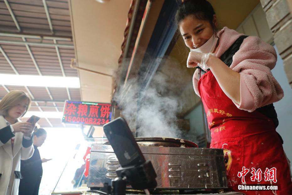 煎餅を焼きながら、ネットライブ放送を配信してネットユーザーと交流する黃璐瑤さん（撮影?殷立勤）。