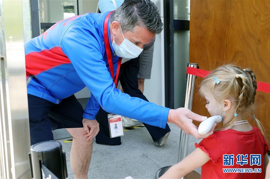 5月13日、蘇州シンガポール國際學(xué)校の校門で、登校を再開した外國籍の學(xué)生の體溫を測定する教員（撮影?華雪根）。