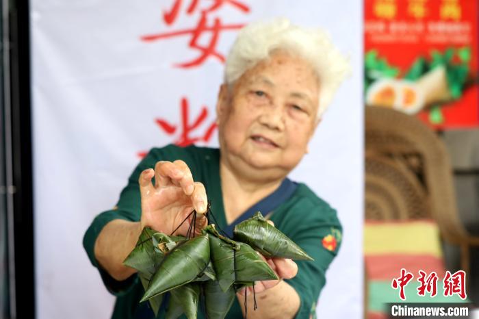3分間で8個包み終わったちまきを見せる、この道數(shù)十年のおばあちゃん（撮影?呂楊）。