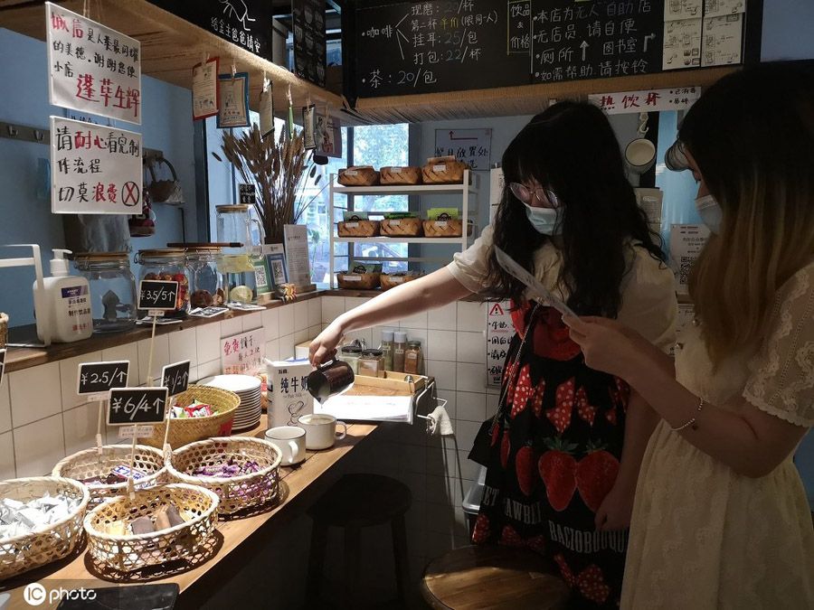 店主が手描きしたイラストを見ながら、自らコーヒーを淹れる2人の客（寫真著作権は東方ICが所有のため転載禁止）。