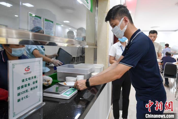 食事をすませ、食器回収場所に設(shè)置された秤に自分の食器を乗せる人（撮影?楊華峰）。