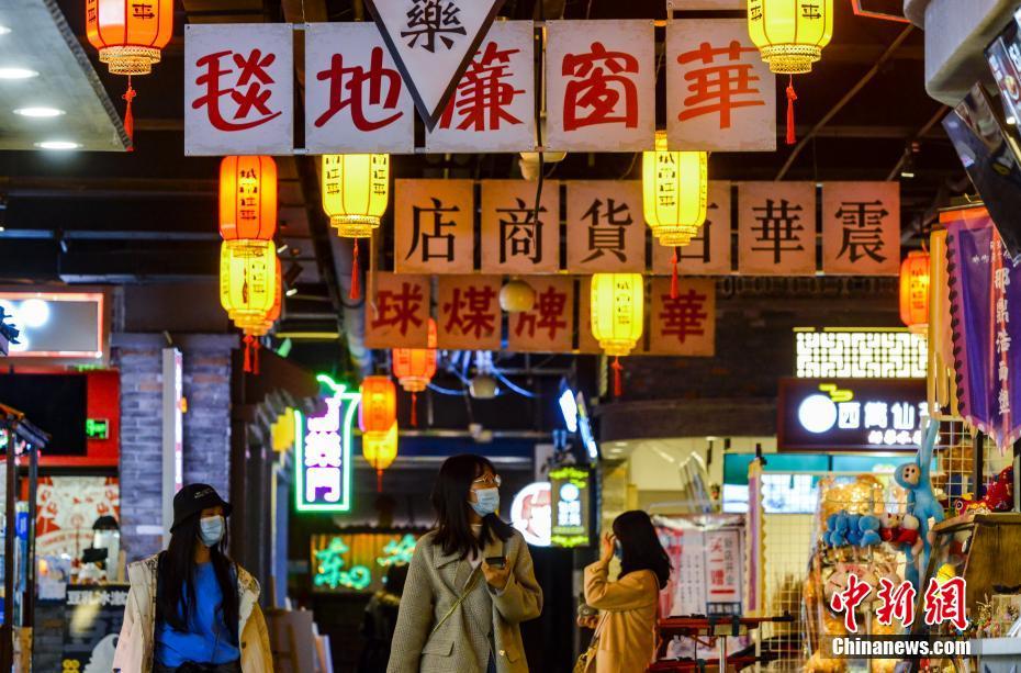 11月2日、新疆維吾爾（ウイグル）自治區(qū)烏魯木斉（ウルムチ）市にこのほどオープンした「ノスタルジー」をテーマとしたグルメ街で、昔のバス停の前を通り過ぎる、食事に訪れた市民（撮影?劉新）。