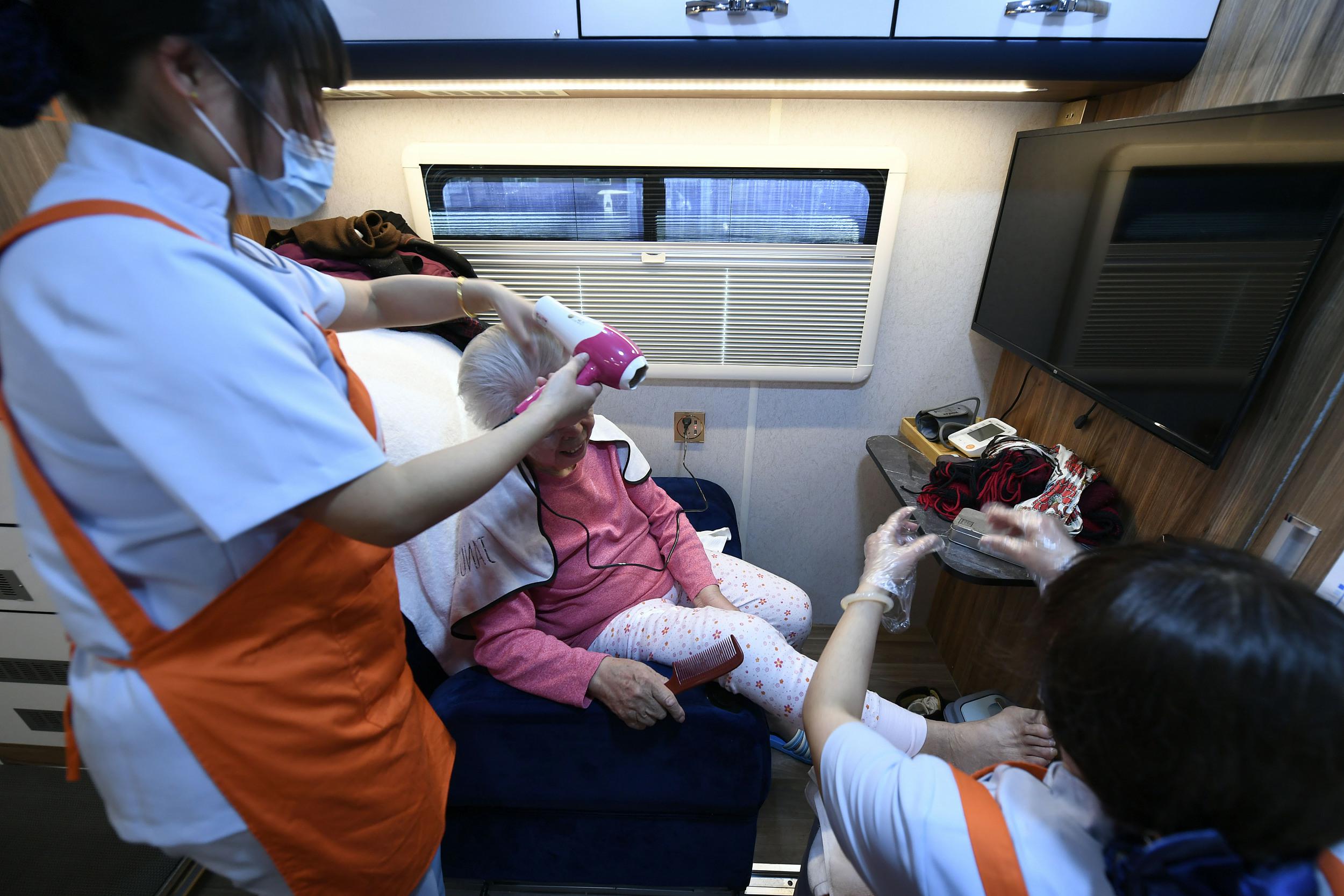 入浴ヘルパーの介助を受けながら入浴サービスを受けるお年寄り。