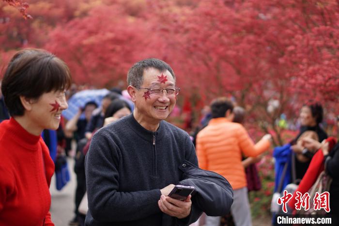 もみじのシールを顔に貼って、春もみじの美しい景色を楽しむ観光客（撮影?陳鑫）。