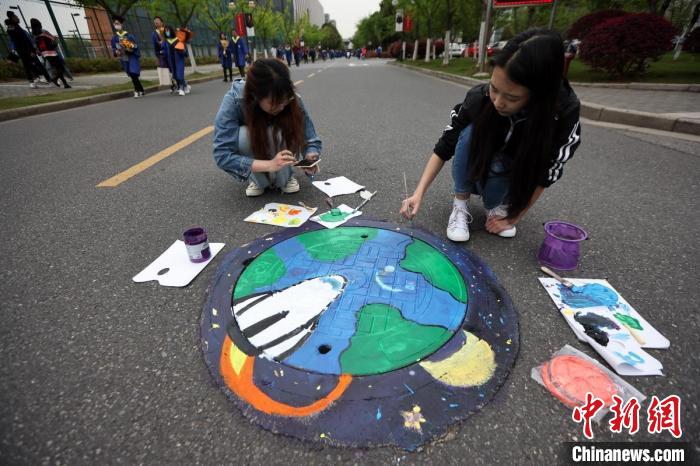 校內(nèi)メインストリートのマンホールに宇宙をモチーフとしたデザインをペイントする學(xué)生（撮影?泱波）。