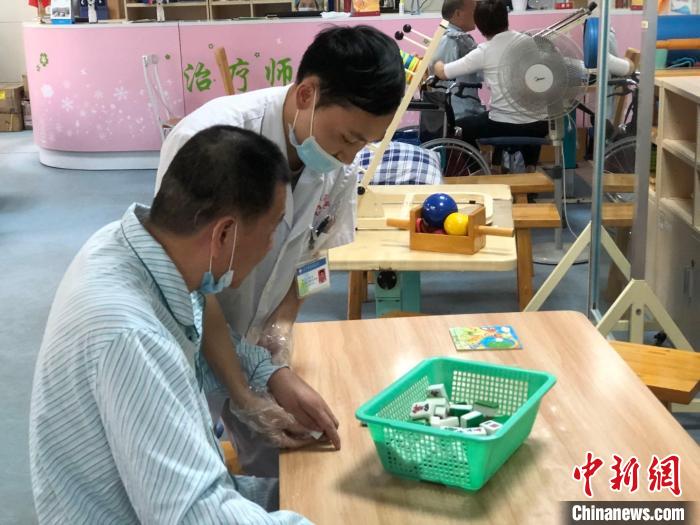 リハビリ室で、麻雀を通じてリハビリ訓練を進める患者（撮影?孫秋霞）。