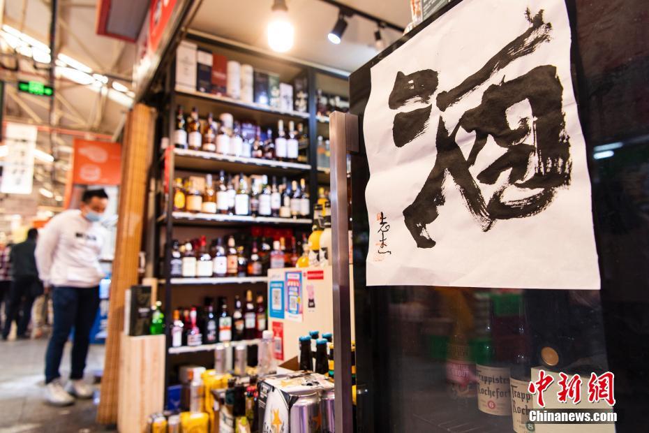 5月5日、買い物客の注目を集めていた北京三源里野菜市場內(nèi)のある酒屋に掲げられた毛筆の「酒」という大きな文字（撮影?侯宇）。