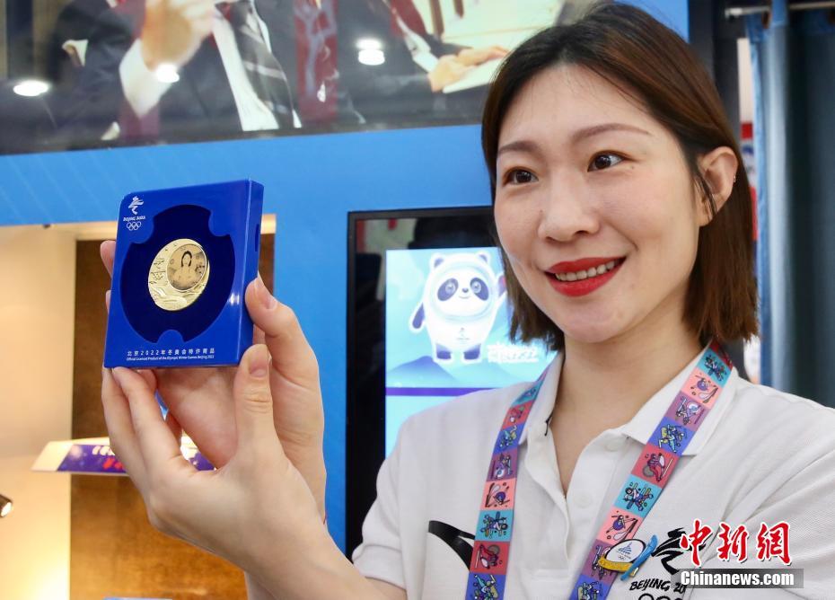 本人の肖像畫がデザインされたピンバッジを掲げる2006年トリノ冬季五輪のフィギュア?スケートペア銀メダリスト張丹さん（撮影?易海菲）。