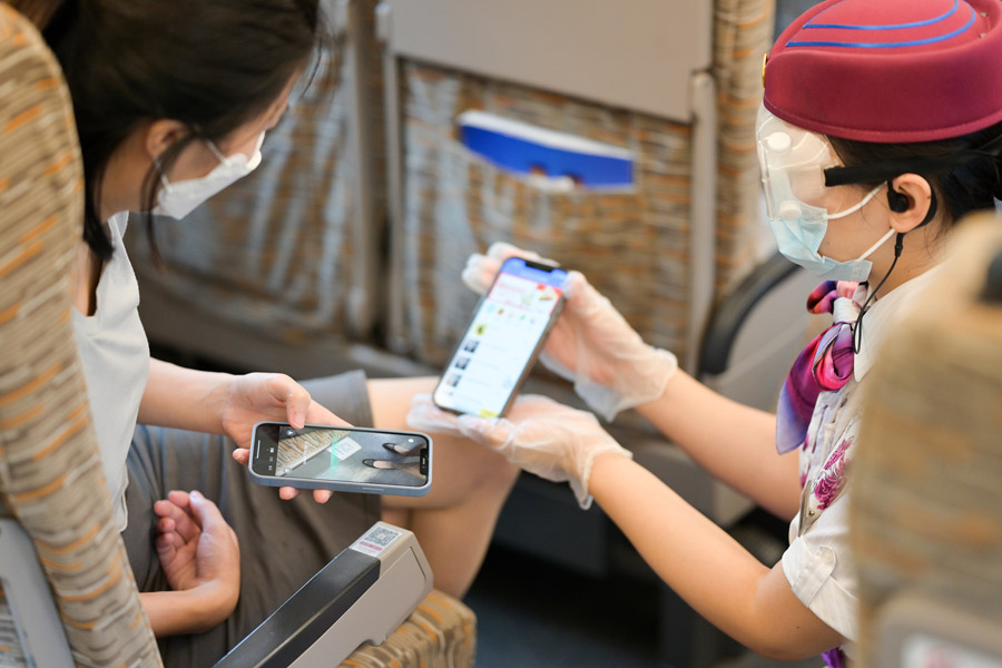 8月17日、重慶北駅から成都東駅に向かう列車「G8608號」內で、微信（WeChat）の「オンライン食事オーダー」ミニプログラムの使い方を説明する女性乗務員（寫真著作権はCFP視覚中國が所有のため転載禁止）。