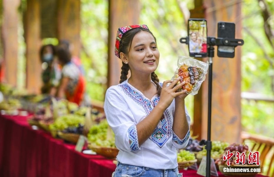 ブドウ棚の下でライブ配信を行い、ネットを通じて特色ある農(nóng)産物を紹介?PRするパーソナリティー（撮影?劉新）。