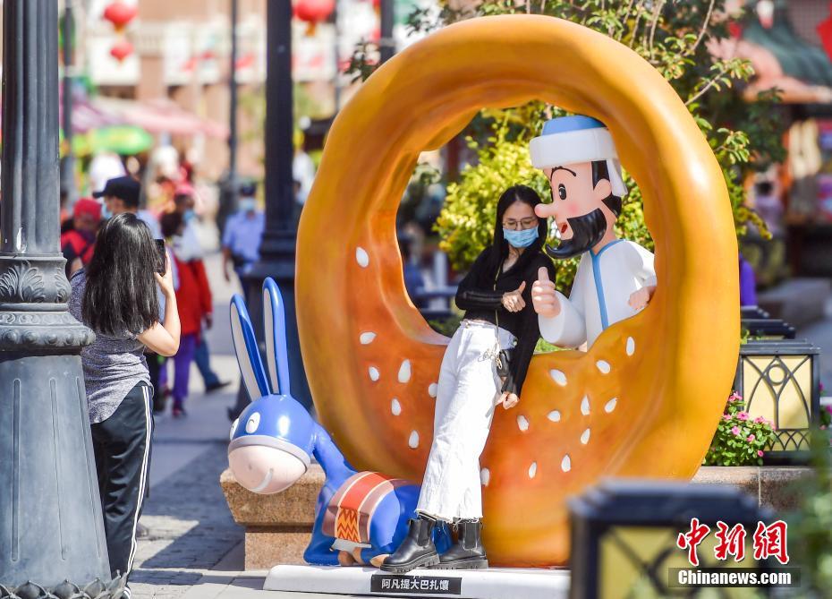 「阿凡提（エペンディ）」のキャラクターオブジェと記念寫真を撮影する観光客（撮影?劉新）。