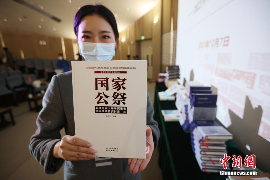 「國(guó)家追悼日-南京大虐殺犠牲者國(guó)家追悼日資料集8」を見(jiàn)せるスタッフ（撮影?泱波）。