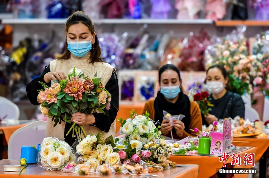 12月8日、新疆維吾爾（ウイグル）自治區(qū)烏魯木斉（ウルムチ）市沙依巴克（サイバグ）區(qū)新居社區(qū)（コミュニティ）花蕓加工作業(yè)所で、シルクフラワー製作に追われる同作業(yè)所で働くコミュニティ住民（撮影?劉新）。