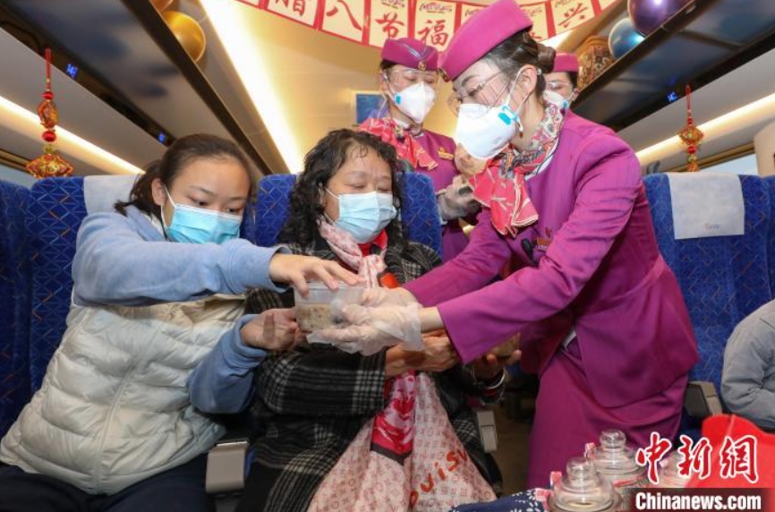 貴州省畢節(jié)市で、乗客に臘八粥を配るC5980號(hào)の乗務(wù)員（撮影?瞿宏倫）。