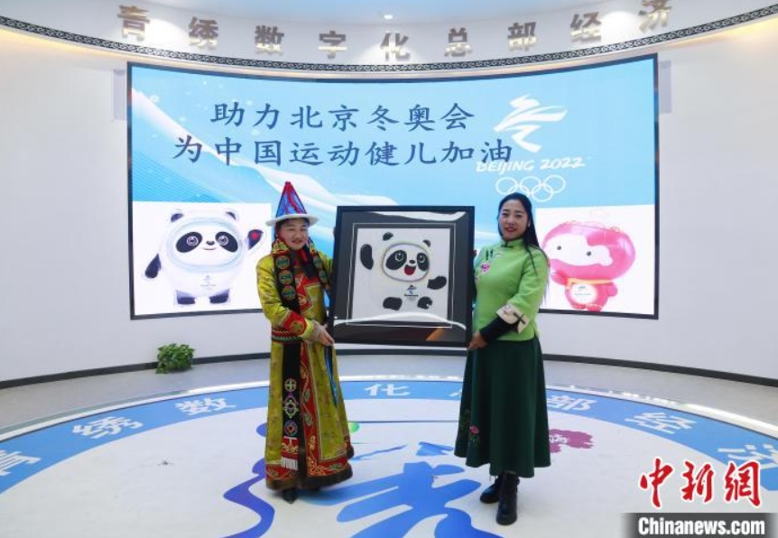 青海刺繍作品「ビン?ドゥンドゥン」を見せる刺繍職人（撮影?馬銘言）。