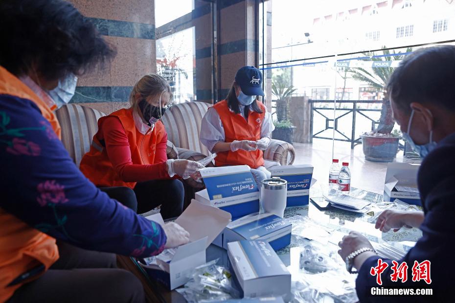 抗原検査キットが入った箱を整理するボランティアに參加した米國人女性のエリカさん（撮影?殷立勤）。