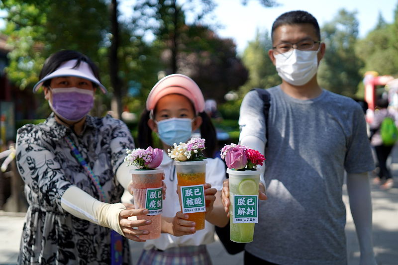 6月1日、「PCR検査済」、「ワクチン接種済」、「封鎖解除済」とそれぞれ書かれた3種類の「グリーンコード」をデザインした特製カップを見せる親子連れ（寫真著作権はCFP視覚中國が所有のため転載禁止）。