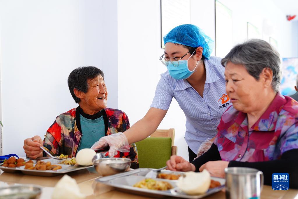 山東省浜州市恵民県何坊街道の「孝善食堂」で、高齢者のお盆にマントウをのせる職員（9月25日撮影?廓緒雷）。