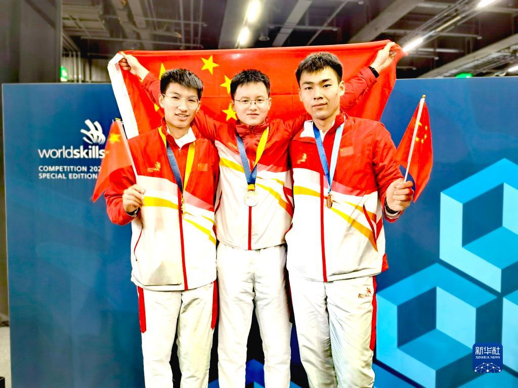 10月15日、スイス?バーゼルで開催された2022年技能五輪國際大會（特別開催）の建具の部門で金メダルを獲得し、表彰式後に記念寫真を撮影する中國の邵茹鵬選手（寫真左）、家具の部門で金メダルを獲得した中國の李徳鑫選手（寫真中央）、建築大工の部門で敢闘賞を手にした中國の王縦橫選手（攜帯端末よる撮影）。