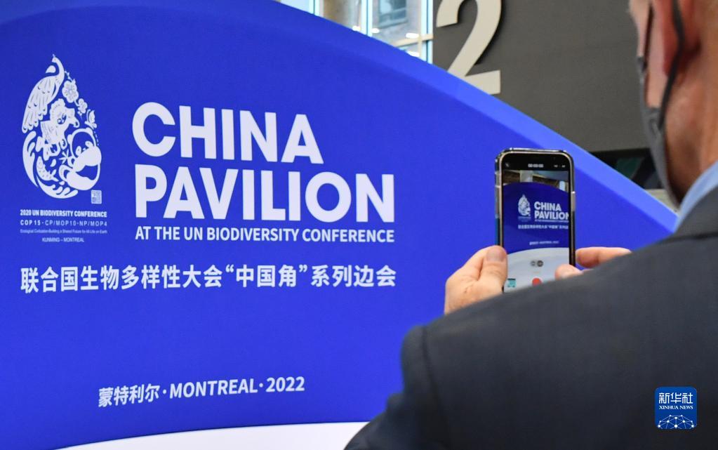 カナダ?モントリオールで開(kāi)幕した國(guó)連生物多様性條約第15回締約國(guó)會(huì)議（COP15）第2部のチャイナパビリオンで、記念寫(xiě)真を撮影する會(huì)議參加者（12月7日撮影?連漪）。