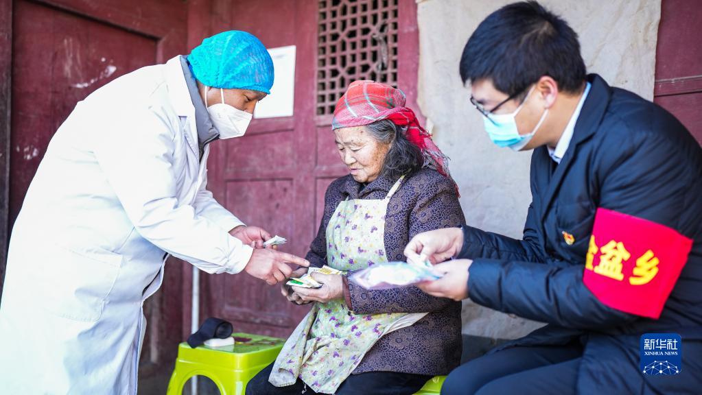 六盤水市鐘山區(qū)金盆苗(ミャオ)族彝(イ)族郷営盤村で巡回診療を行い、村民に薬を配る醫(yī)療従事者と共産黨?先鋒隊の隊員（寫真右、1月6日撮影?陶亮）。