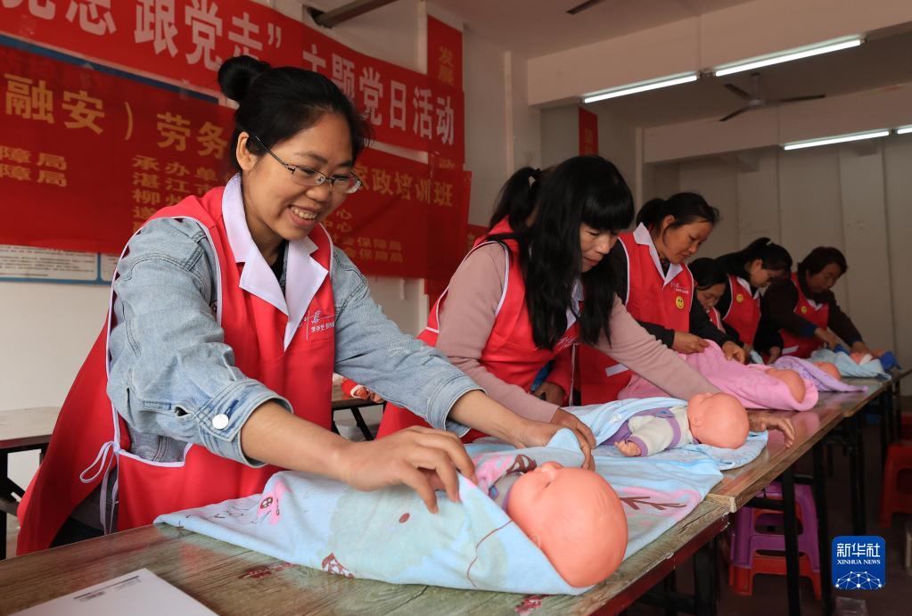 貧困者支援策によって県外から移り住んだ人々が暮らす融安県?融康社區(qū)（コミュニティ）で、赤ちゃんの世話について學ぶ人々。（3月14日撮影?黃孝邦）