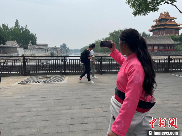 故宮を囲む堀をスマホで撮影する鬧増拉毛さん（撮影?袁秀月）。