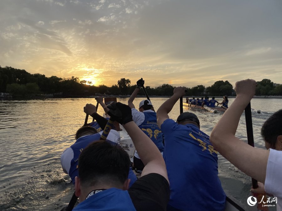 後海の向こうに沈む夕陽に向かってドラゴンボートを漕ぐ（撮影?勝又あや子）。