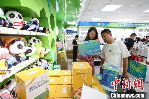 8月1日、成都の春熙路にある第31回FISU夏季ワールドユニバーシティゲームズ（成都ユニバ）の公式ライセンス商品オフィシャルショップで、大會(huì)公式マスコット「蓉寶」の記念グッズを選ぶ観光客。（撮影?瞿宏倫）