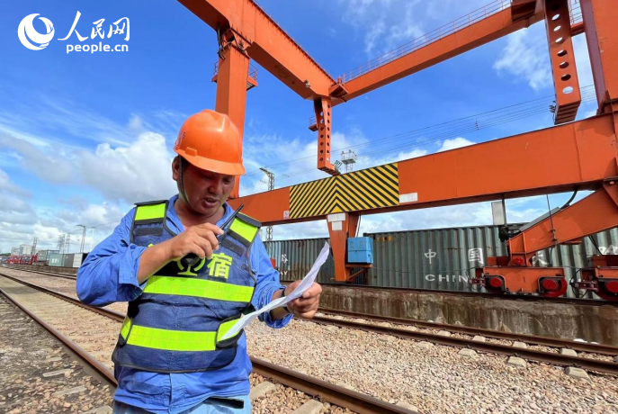 クレーン運(yùn)転士との間でコンテナを照合し、積み込み作業(yè)を行う作業(yè)員。（撮影?皇甫萬里）