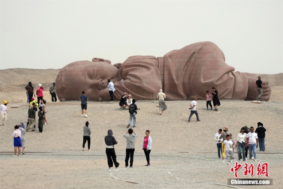 瓜州戈壁國(guó)際雕塑アートギャラリーで、大型彫刻作品「大地の子」を鑑賞する観光客（8月30日撮影?毛建軍）。