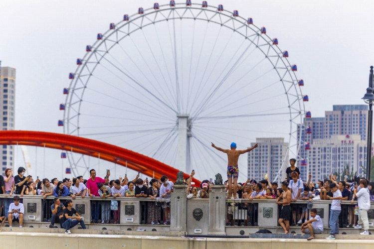 2023年8月27日、天津市の獅子林橋で、観光客とやりとりする飛び込み愛(ài)好者。（寫(xiě)真提供は視覚中國(guó)）